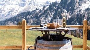 A wooden table with glasses and a bottle, set against a mountain backdrop. - Etable Des Crosets (Val d'Illiez)