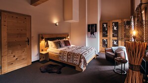 A wooden-framed bedroom with a bed, nightstands, a chair, and a wall-mounted light fixture. - Etable Des Crosets (Val d'Illiez)