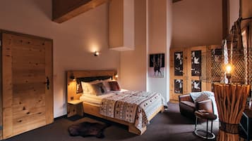 Quarto com estrutura de madeira, cama, mesas de cabeceira, uma cadeira e luminária fixada na parede.