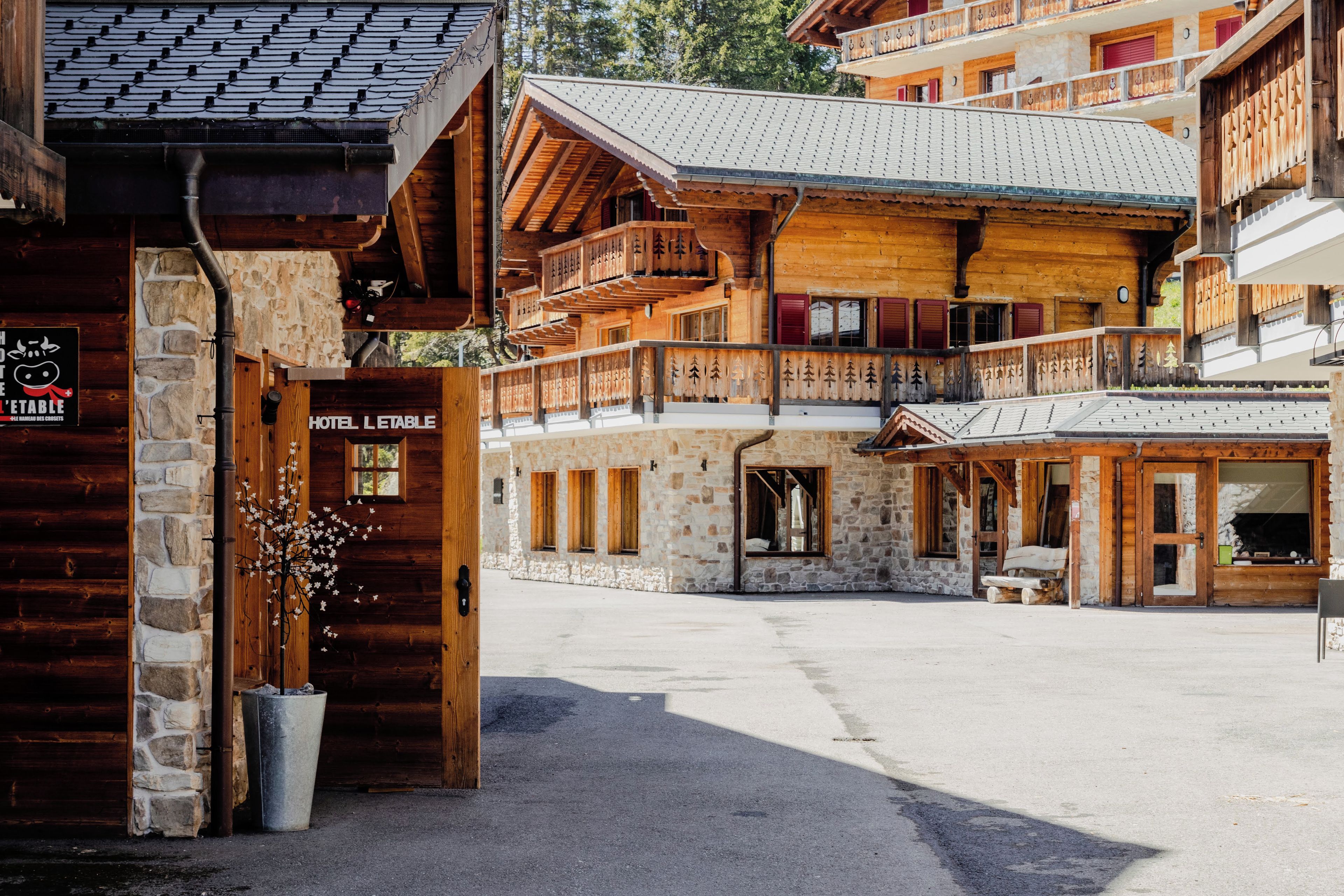 A wooden building with balconies, a stone facade, and a sign reading 'HOTEL L'ETABLE.'