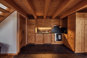 A wooden interior with a kitchen area, including cabinets, a sink, and a stove. - Etable Des Crosets (Val d'Illiez)