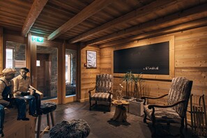 A wooden interior with a stone wall, a wooden bench, a chair, a table, and a fireplace. - Etable Des Crosets (Val d'Illiez)