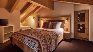 Ein Schlafzimmer mit Holzboden, einem Bett mit gemusterten Betttextilien, einem Nachttisch und einem Fernseher.