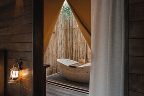 Ein Wellnessbereich mit freistehender Badewanne, Holzwänden und einer Laterne.