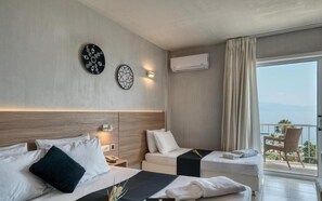 A hotel room with two beds, a bedside table, a wall-mounted air conditioner, and a balcony with a view. - Black And White Resort (Xylokastro-Evrostina)