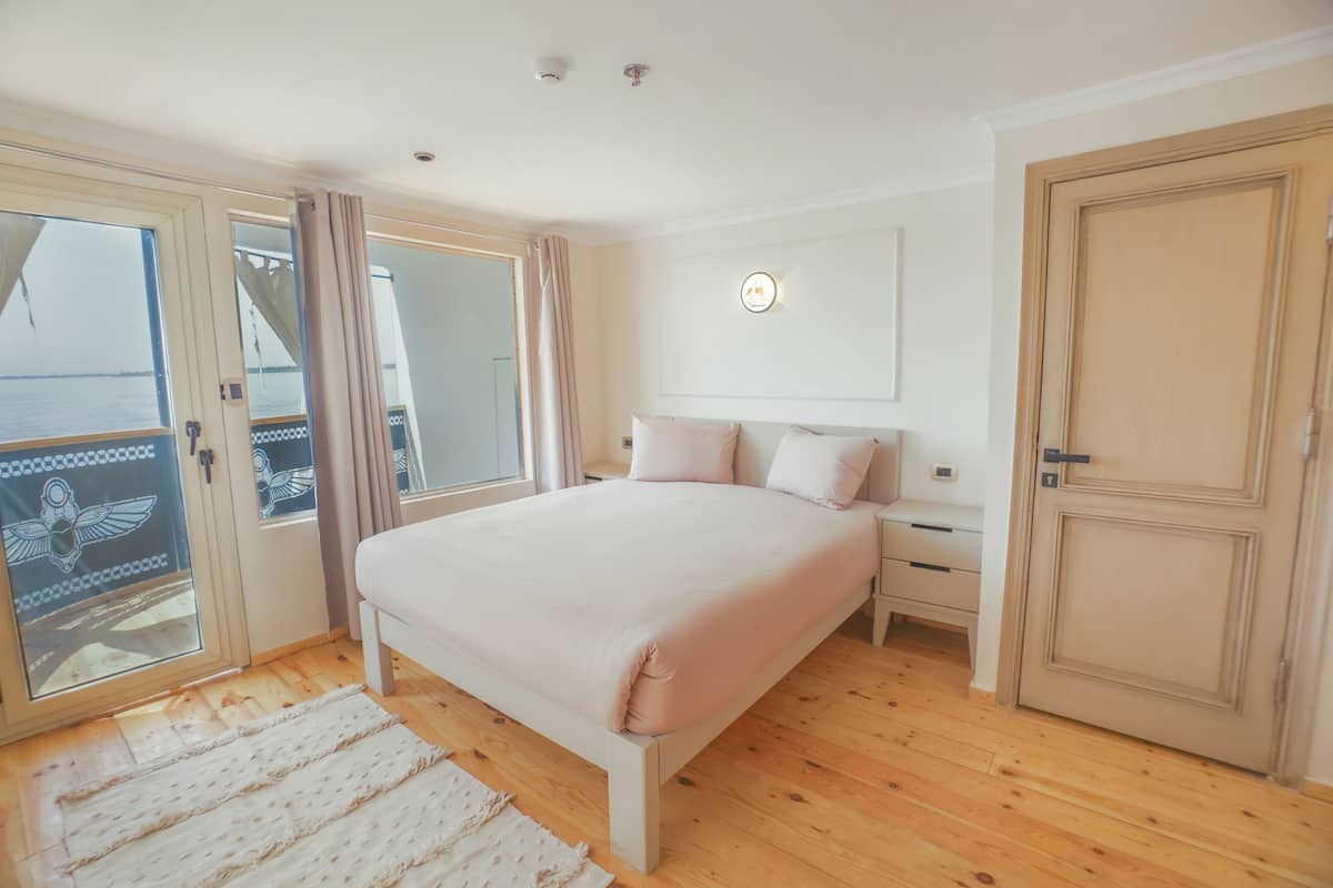Une chambre à coucher comprenant un lit, une table de chevet, une armoire et une porte-fenêtre coulissante donnant sur un balcon.