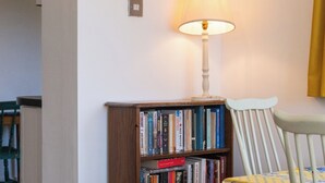 En reol med bøger, en lampe og en stol i et rum.