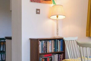 A bookshelf with books, a lamp, and a chair in a room. - Peaceful 2BDR Escape Near Primrose Hill (Greater London)