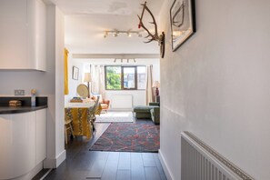 A hallway leading to a dining area with a table and chairs, a radiator, and a window with a view. - Peaceful 2BDR Escape Near Primrose Hill (Greater London)