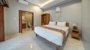 A bedroom with a bed, wooden wardrobe, bedside table, and a wall-mounted macrame piece. - Q~la Villas (Legian)
