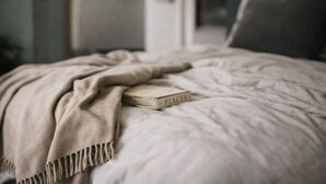Una cama con un edredón color beige y un libro titulado 'PLACES'.
