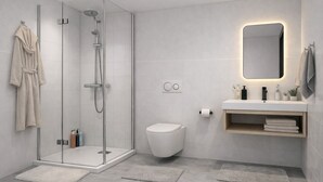 Un baño moderno con ducha de vidrio, inodoro, lavamanos con espejo y toallero.