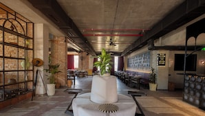 A spacious lobby with a central seating area, a brick wall with shelves, and a ceiling fan. - The Wine Station Hotel Tsinandali (Telavi)