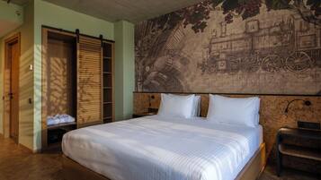 Habitación de hotel con una cama grande, un armario de madera y un mural de un tren en la pared.