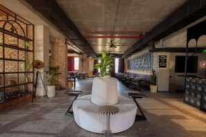Un hall d’entrée spacieux avec un espace salon central, un mur en briques doté d’étagères et un ventilateur de plafond.
