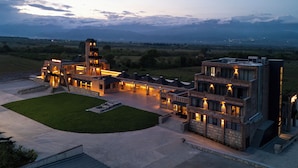 A large, modern building with multiple levels, a central courtyard, and a view of distant mountains. - The Wine Station Hotel Tsinandali (Telavi)