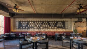 Un restaurante con mesas y sillas, una pared con diseños circulares y una zona de recepción.
