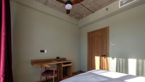 A bedroom with a bed, a desk, a chair, and a door. - The Wine Station Hotel Tsinandali (Telavi)