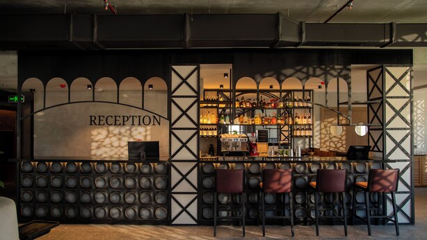 A reception area with a bar, seating, and a display of bottles. - The Wine Station Hotel Tsinandali (Telavi)