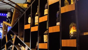 A bar area with shelves containing bottles of alcohol, a staircase, and a wooden structure. - Poolside Viewbguesthouse (Kigali)