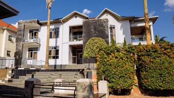 A multi-story building with balconies, a stone staircase, and a well-maintained garden.