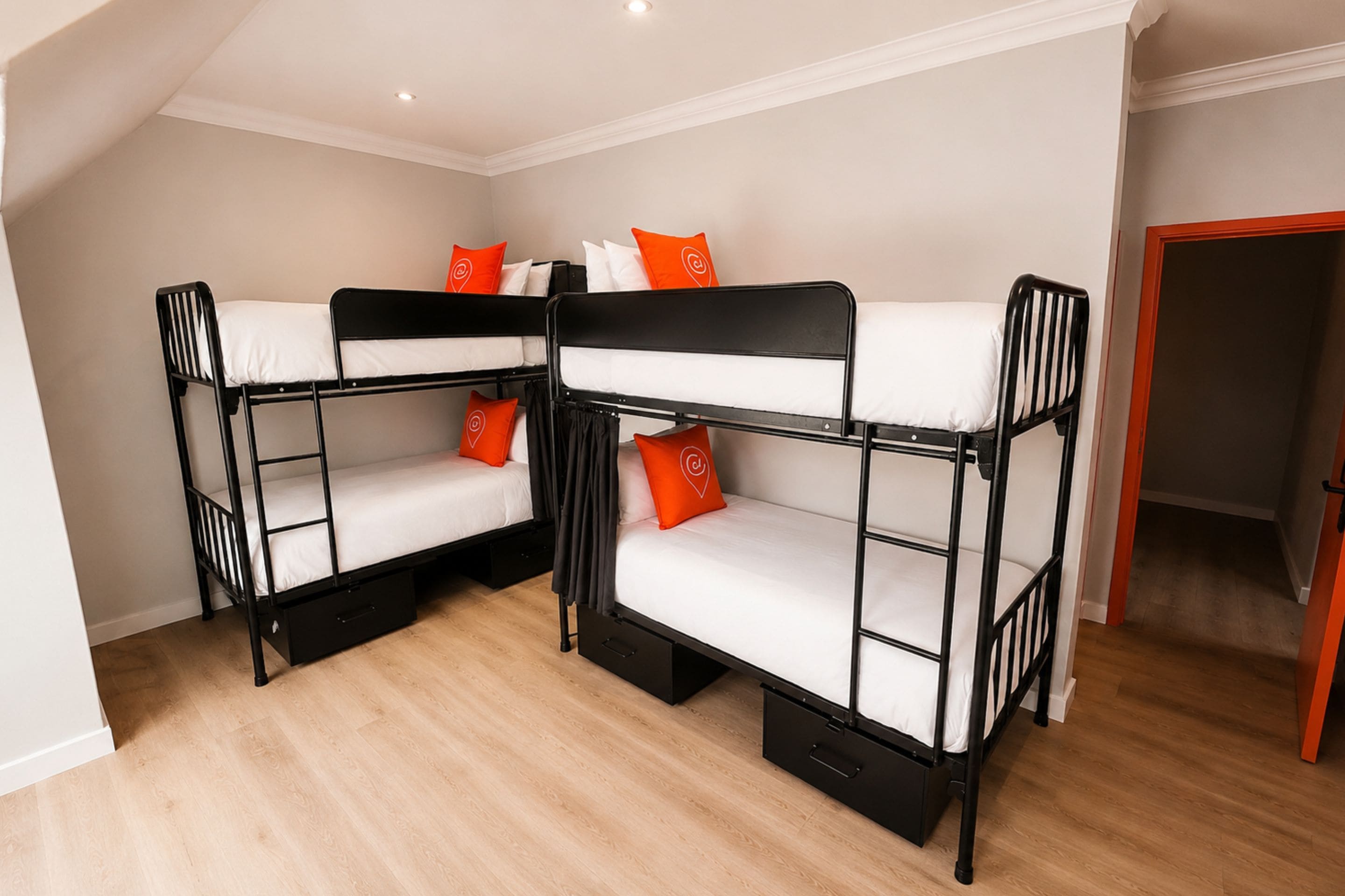 A room with bunk beds, a wooden floor, and a door.
