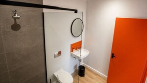A modern bathroom with a shower, toilet, sink, and a mirror.