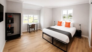 Een hotelkamer met een bed, een bureau, een stoel, een kledingkast en een raam.