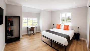 Een hotelkamer met een bed, een bureau, een stoel, een kledingkast en een raam.