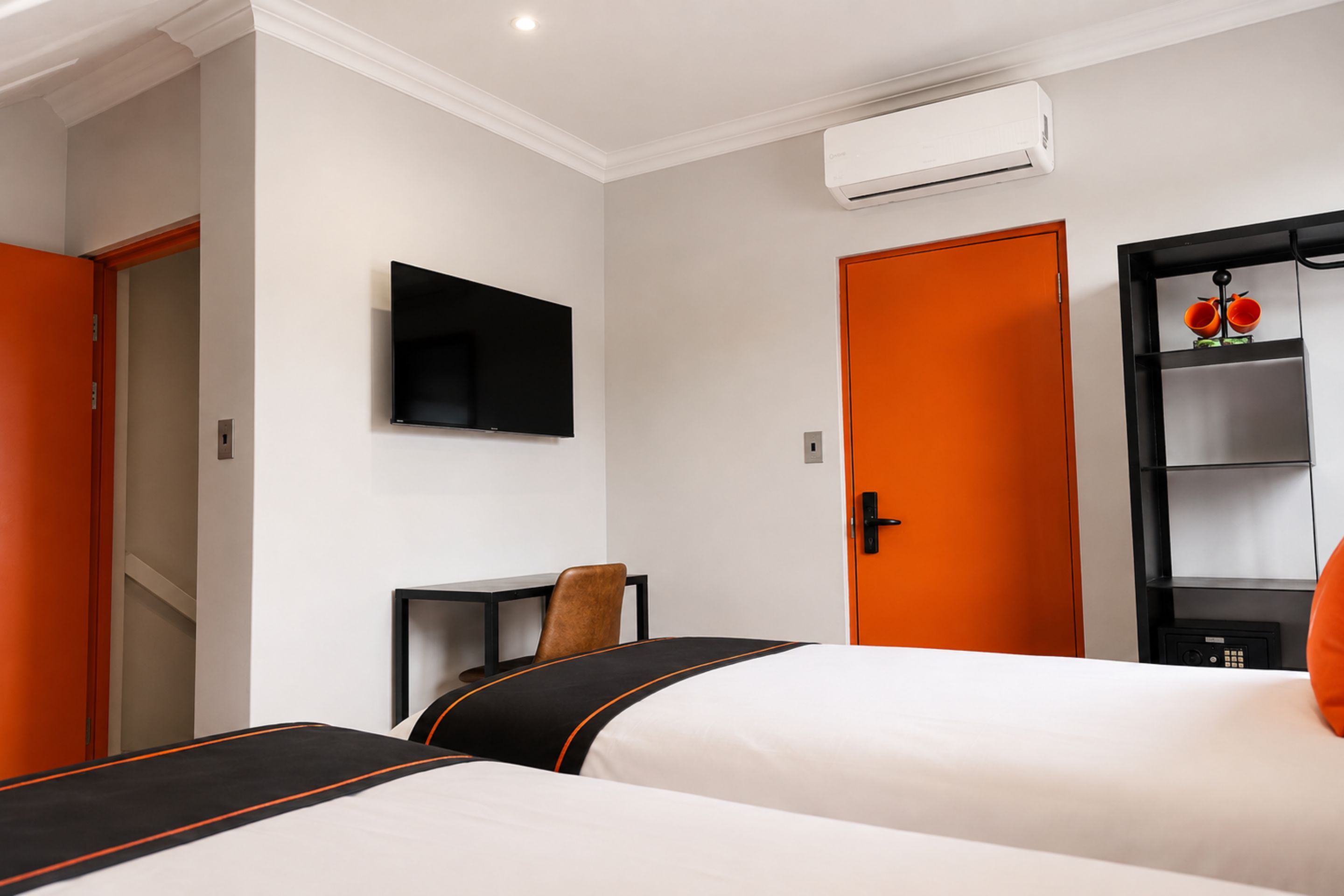 Une chambre d’hôtel avec deux lits, une télévision, un climatiseur et une armoire.