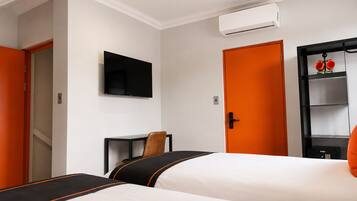 Une chambre d’hôtel avec deux lits, une télévision, un climatiseur et une armoire.