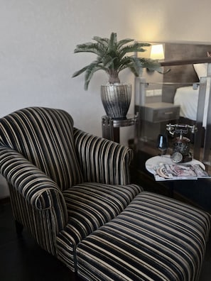 A striped armchair, a potted plant, a small table with a magazine, and a bed in the background. - Le Cannes, A Recall Luxe Hotel, Chiang Mai (Chiang Mai)
