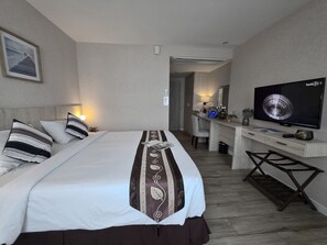 A hotel room with a bed, bedside table, TV, desk, chair, and a framed picture on the wall. - Le Cannes, A Recall Luxe Hotel, Chiang Mai (Chiang Mai)