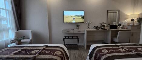 Una habitación de hotel con dos camas, un escritorio, un televisor y una silla.