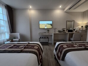 Habitació d'hotel amb dos llits, un escriptori, una televisió i una cadira.