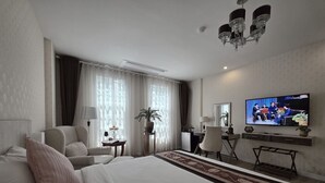 A hotel room with a large bed, a desk with a chair, a television, and a potted plant. - Le Cannes, A Recall Luxe Hotel, Chiang Mai (Chiang Mai)