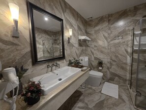 A bathroom with a marble wall, a large mirror, a sink, a shower, and a hairdryer. - Le Cannes, A Recall Luxe Hotel, Chiang Mai (Chiang Mai)