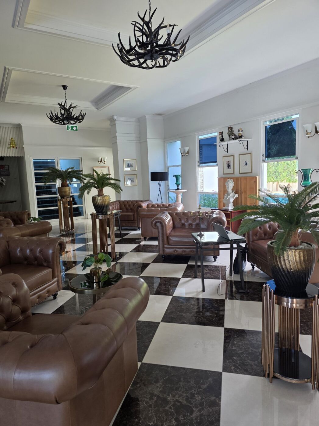 Eine geräumige Lobby mit Ledersofas, einem Schachbrettmuster-Boden und einem Kristallleuchter.