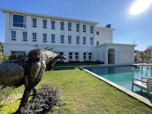 A large white building with a swimming pool and a sculpture of an animal. - Le Cannes, A Recall Luxe Hotel, Chiang Mai (Chiang Mai)