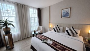 A hotel room with a large bed, a chair, a small table, a potted plant, and a framed picture on the wall. - Le Cannes, A Recall Luxe Hotel, Chiang Mai (Chiang Mai)