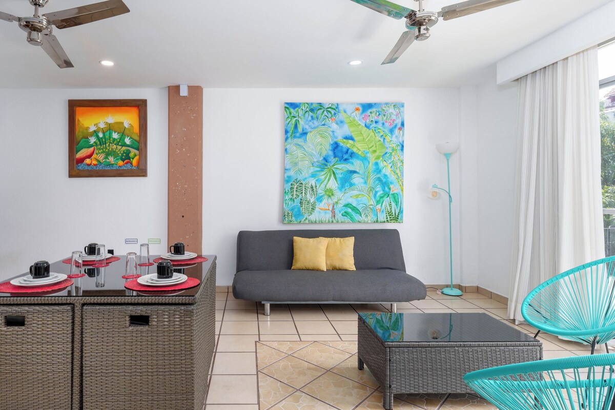 A modern living area with a sofa, a dining table with chairs, a coffee table, and a ceiling fan.