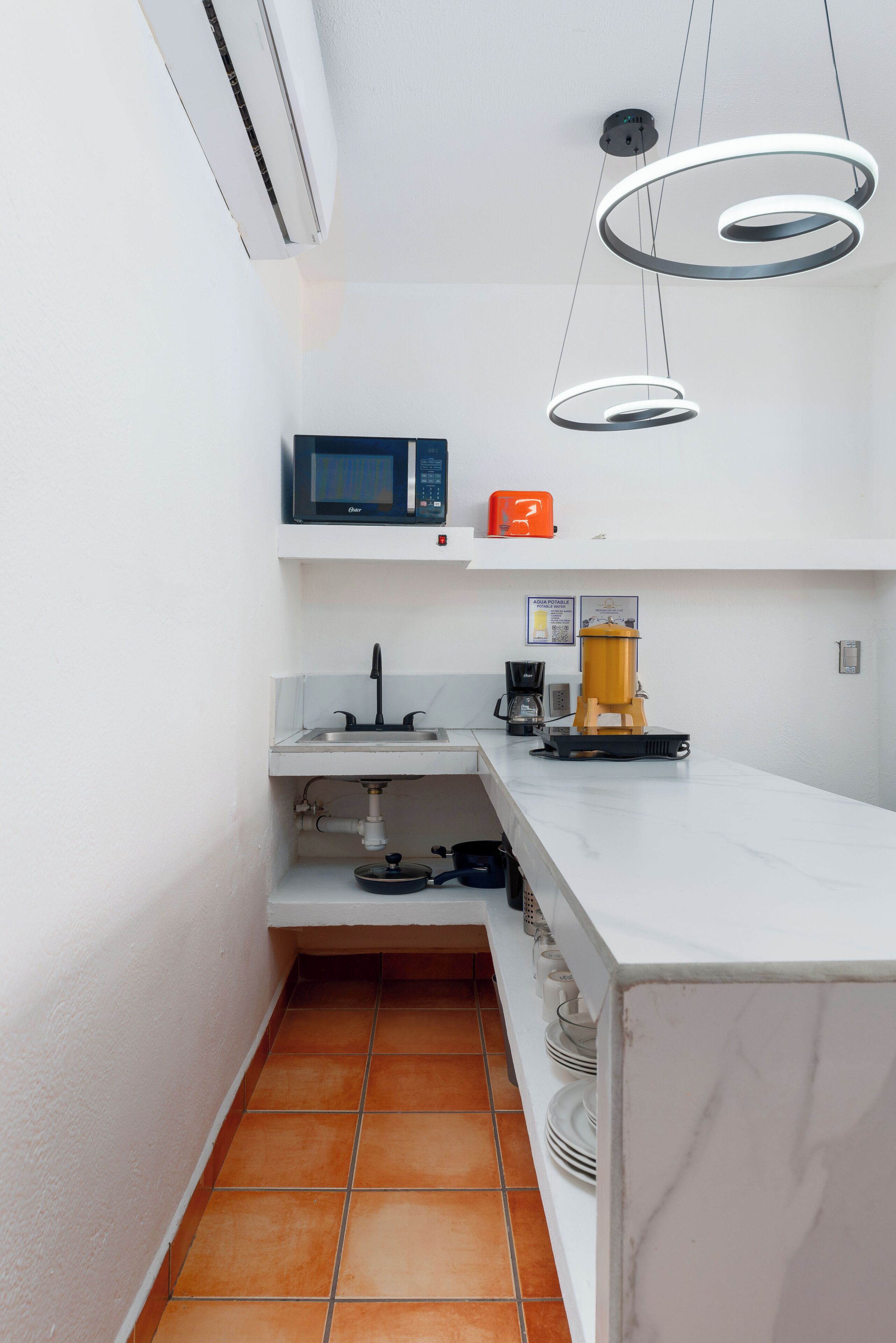 A compact kitchen with a microwave, coffee maker, and a water dispenser.