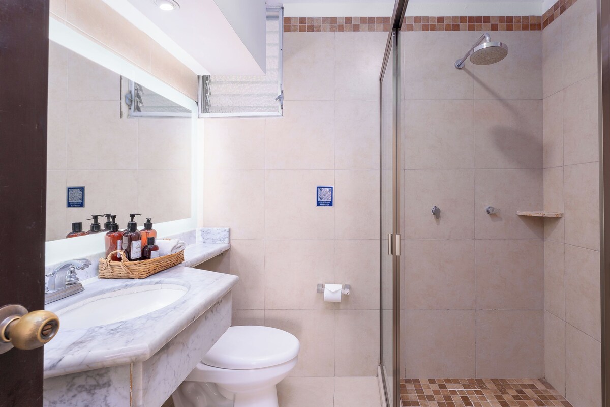 Une salle de bain équipée d’une douche, de toilettes et d’un lavabo en marbre, ainsi que de produits de toilette.