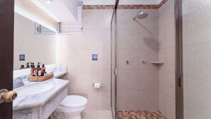 A bathroom with a shower, toilet, and a marble sink with toiletries. - Hotel Casa Chahue (Santa María Huatulco)
