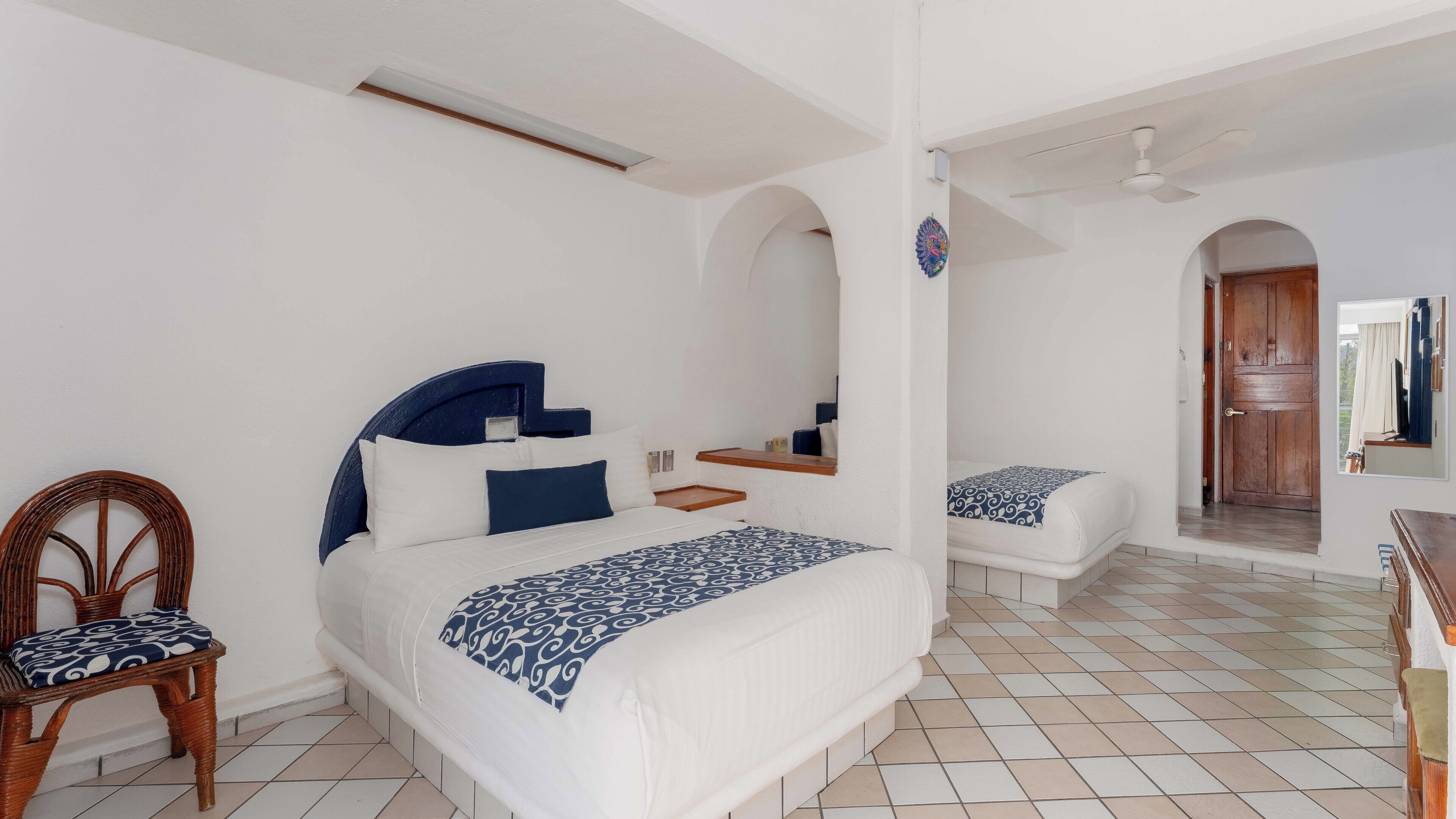 A bedroom with a bed, a chair, a small table, and a wooden door.