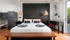 A modern hotel room with a large bed, two bedside tables, a desk, and a kitchenette. - Hotel Casa Chahue (Santa María Huatulco)