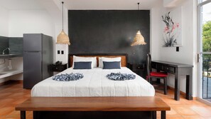 A modern hotel room with a large bed, two bedside tables, a desk, and a kitchenette. - Hotel Casa Chahue (Santa María Huatulco)