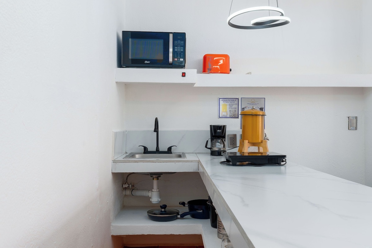 Eine kompakte Küche mit Mikrowelle, Kaffeemaschine und Wasserspender.