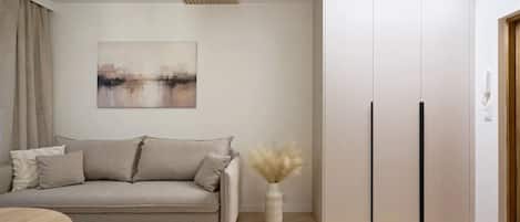 A modern living room with a sofa, a vase with dried plants, and a wardrobe with two doors.