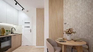 Eine moderne Küche mit Einbauofen, Spüle und Essbereich mit rundem Tisch und zwei Stühlen.